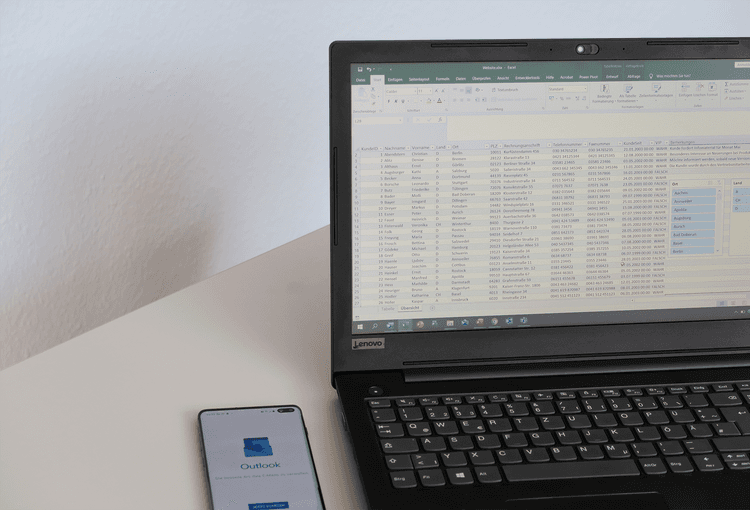 Smartphone mit Outlook-App und Laptop mit Excel-Tabelle
