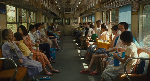 A screenshot from the film 'The Shoplifters' of an old crowded Japanese passenger train.