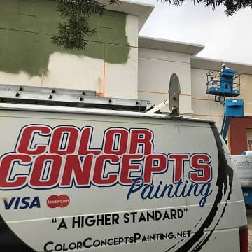 color concepts branded van parked in front of a large commercial building being painted