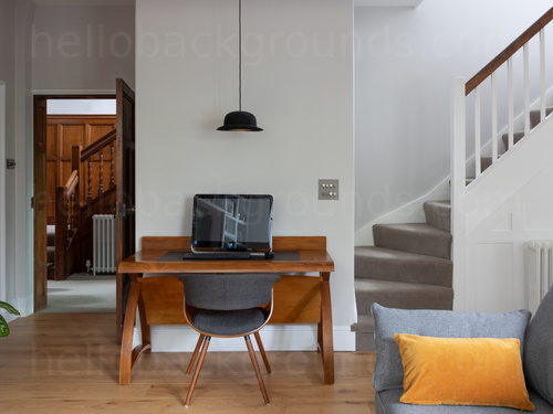 Minimal study area featuring wooden desk with laptop computer at the base of curving staircase Zoom background