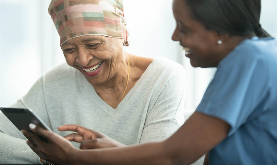 Staff member helps smiling senior woman use an ipad