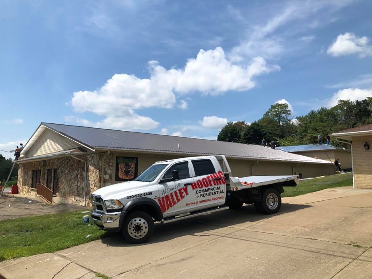 A Valley Roofing truck parks outside one of their latest projects, a big beautiful metal roof.