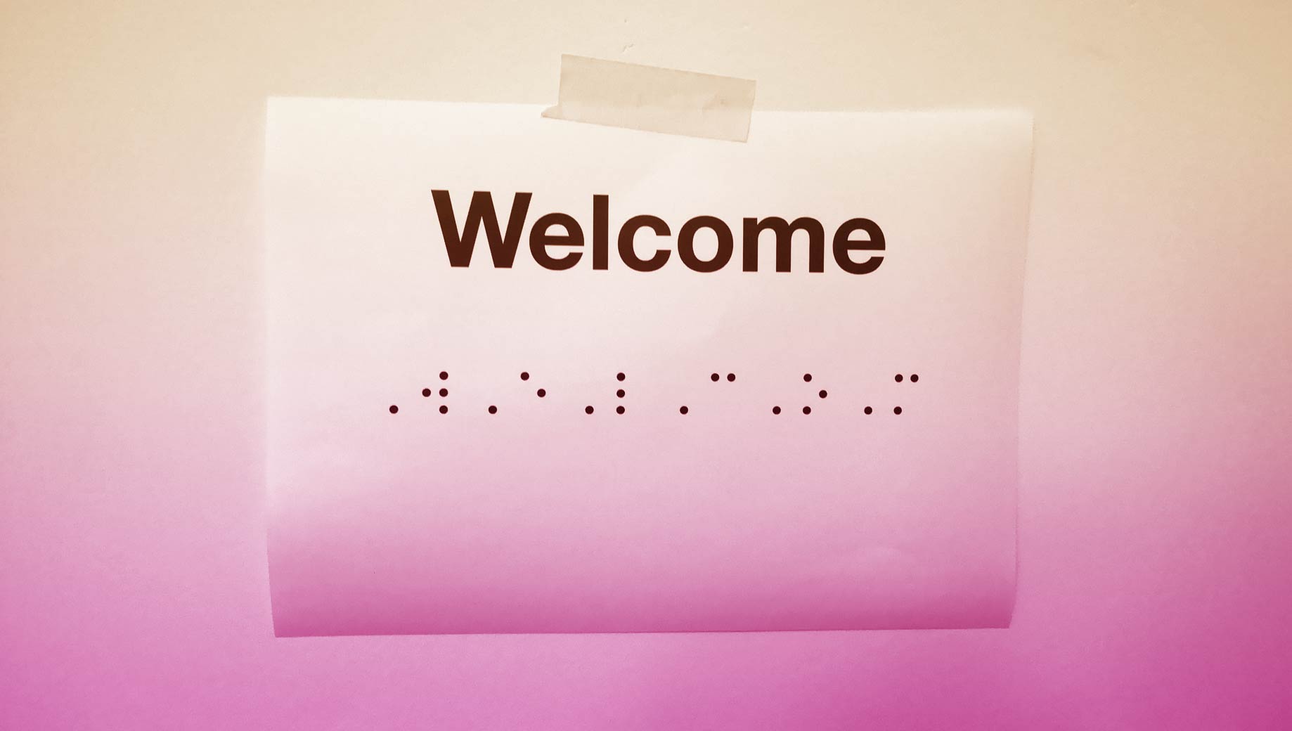 A printed piece of paper that says Welcome in braille