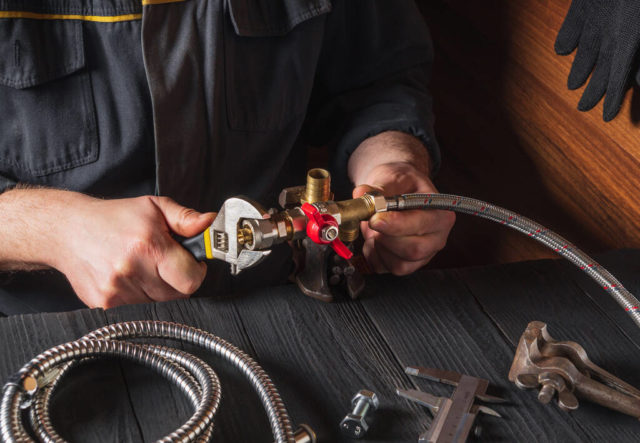 the plumber connects the brass fittings to the faucet with an ad