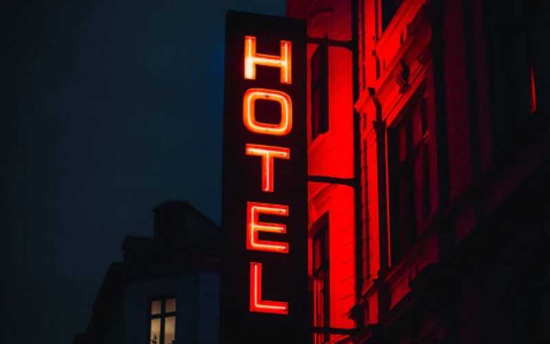 A neon sign at night with a word “hotel”
