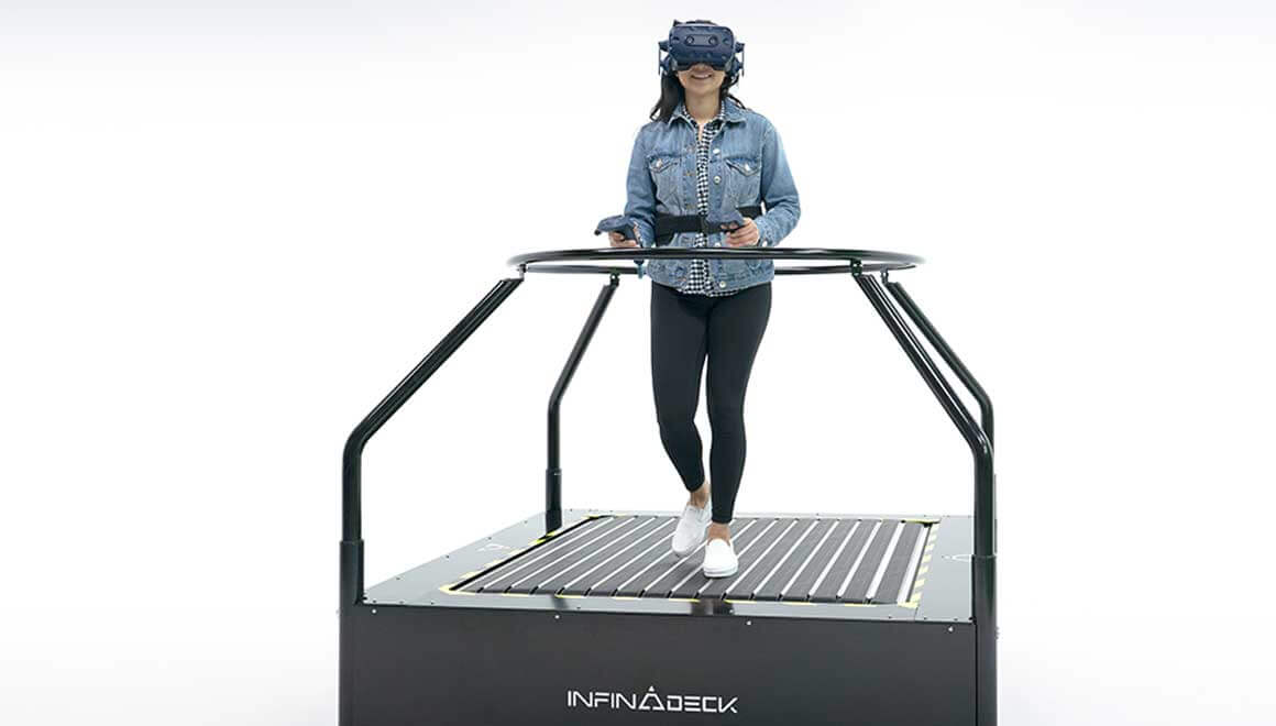 Image of smiling woman wearing VR goggles and experiencing the Infinadeck movement platform.