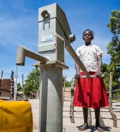Young girl using water pump