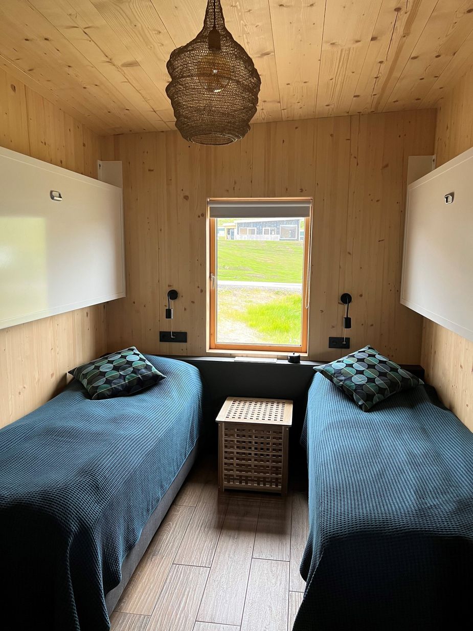 Schlafzimmer mit Fenster und zwei Einzelbetten sowie 2 herausklappbaren Betten