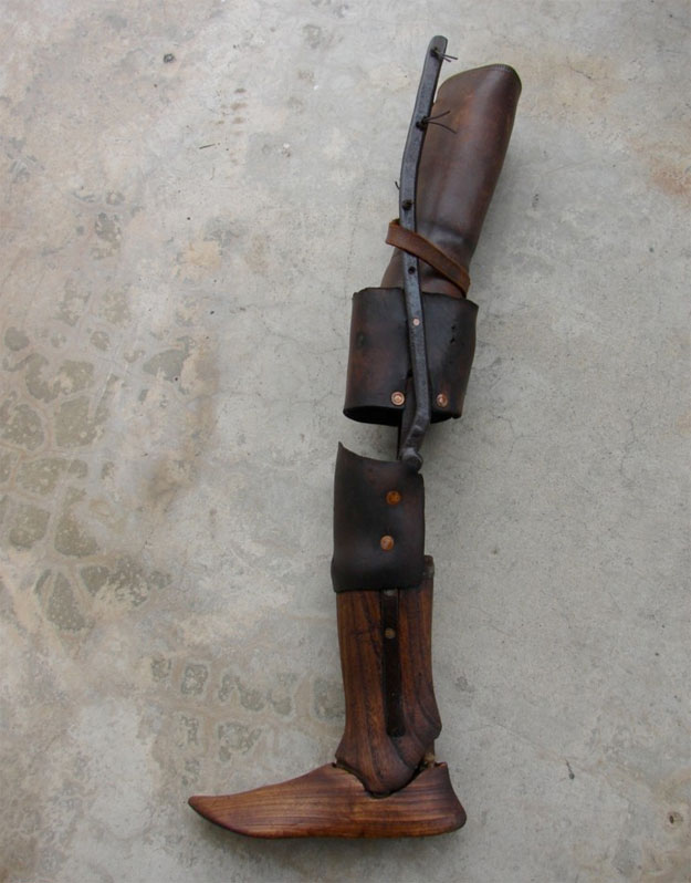 A 19th century wooden leg, pieced together with leather parts at the knees and including a hinged "ankle"