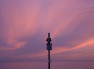 A violet sky with wavy clouds behind a no cycling sign.