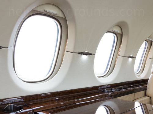 Private jet interior with brown wooden table and cream leather seat Google Meet background