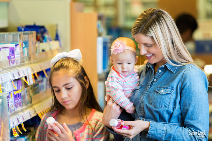 A mom shops at the drug store with her young daughters. Medicine Storage Tips to Keep Your Kids Safe.