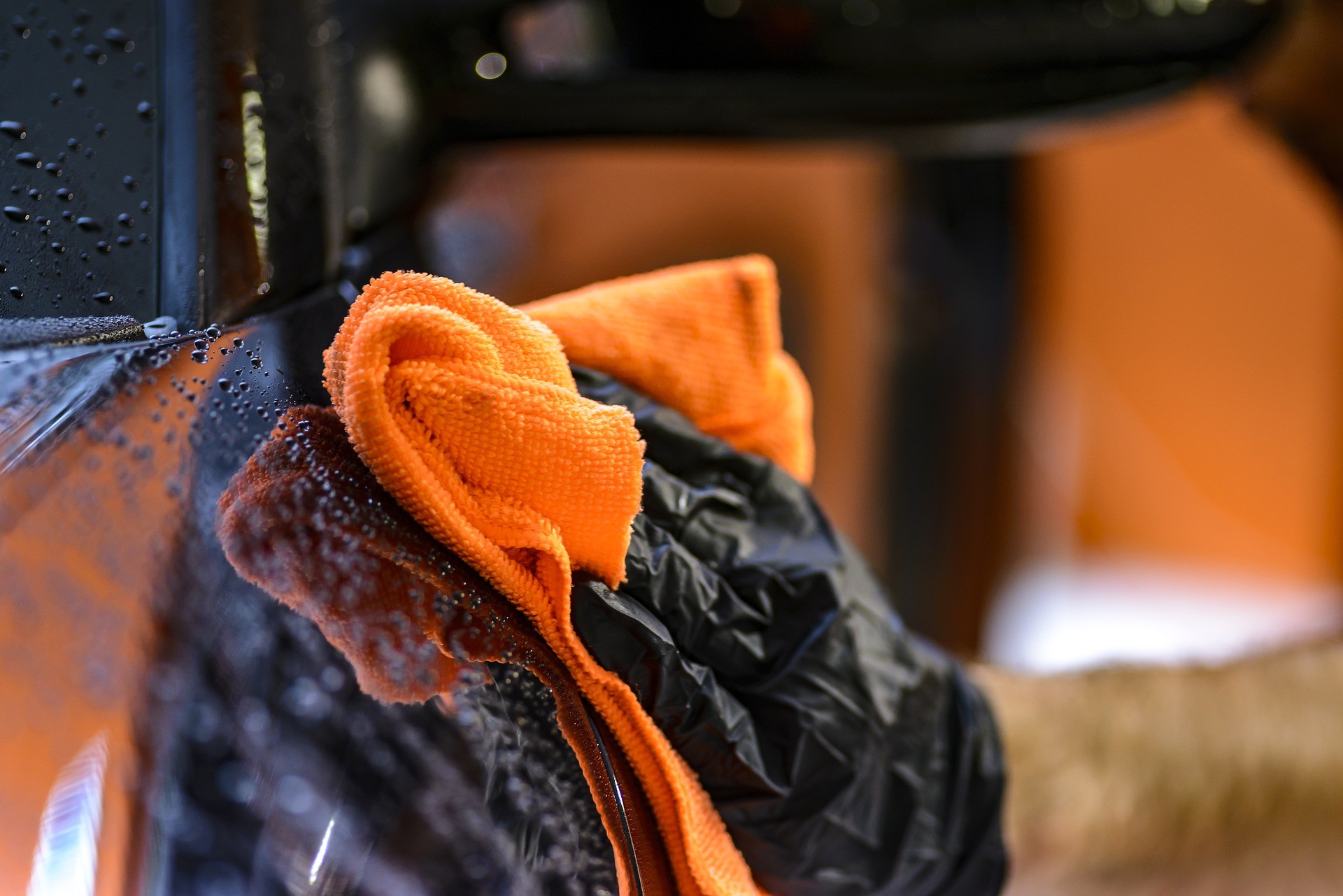 Orange towel drying a wet black car Decatur Autowash better wash