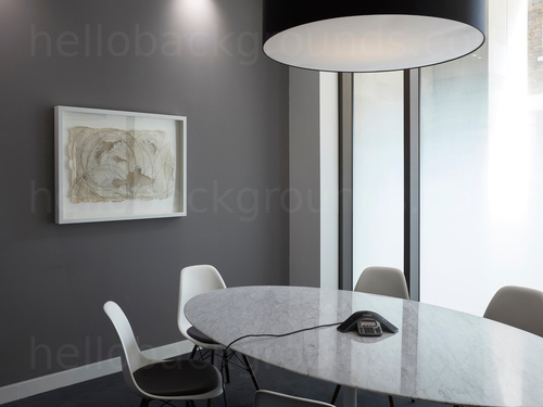 Basic intimate grey colour themed meeting room with oval table and chairs next to wall mounted modern art piece Microsoft Teams background