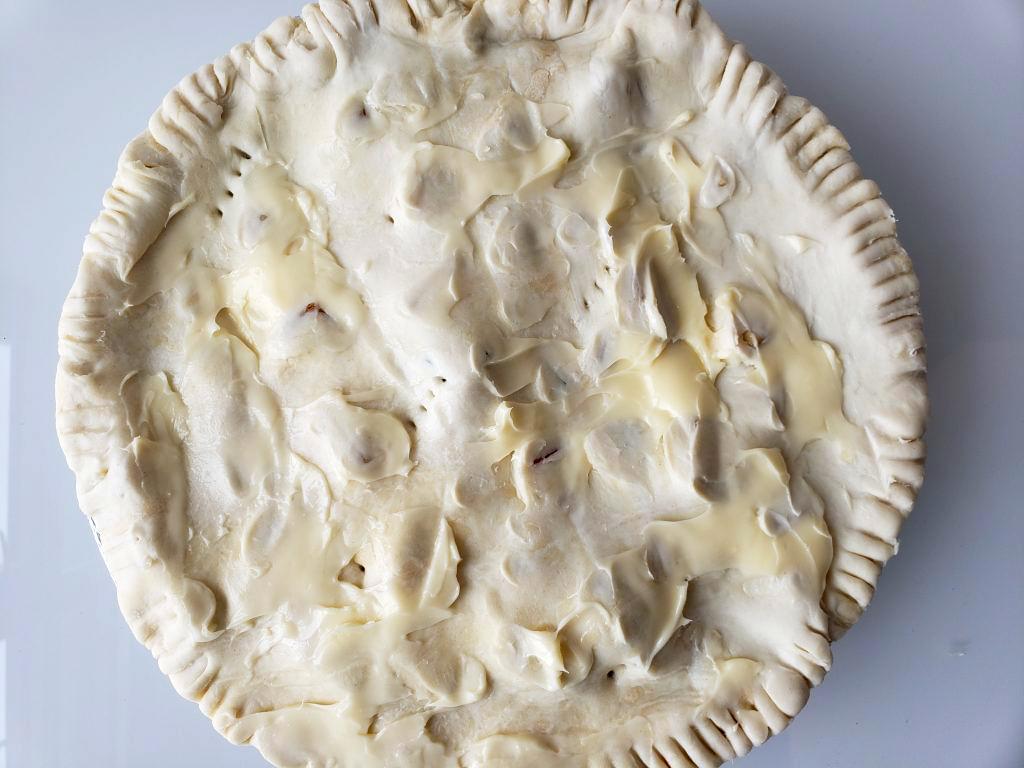 Uncooked vegetable pot pie with butter smeared on top