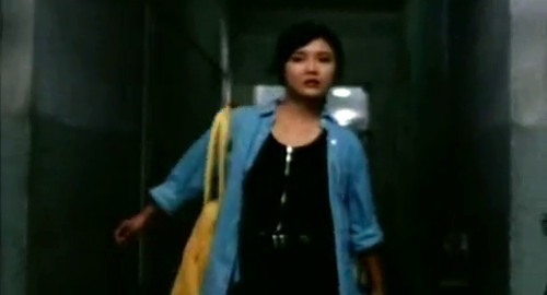 A screenshot of a woman in a jean jacket running worried down a dark hallway. From the Chinese movie 'Frozen'.