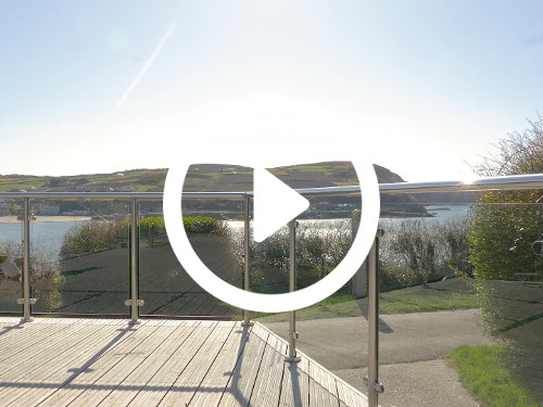 Scenic outdoor waterside terrace with metal framed glass barrier holding views on to body of water and green hills Zoom background