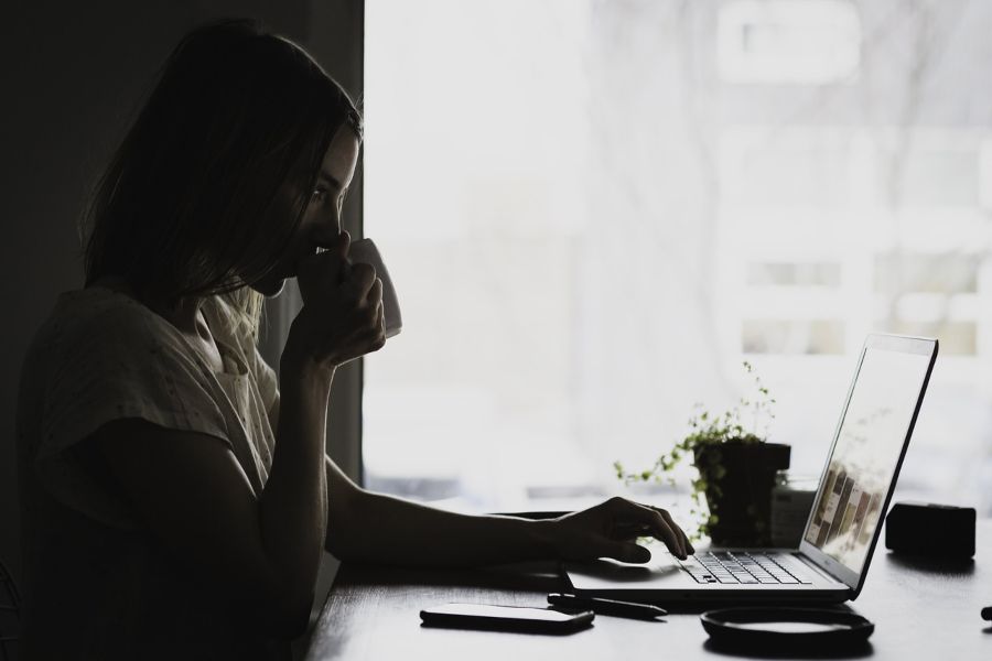 Person working on laptop drinking coffee