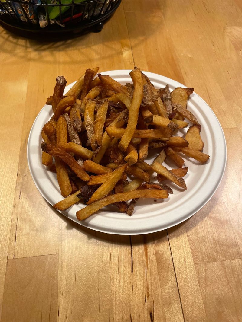 A paper plate with a few handfuls of french fries on it