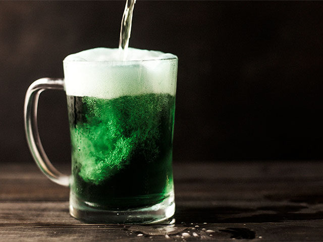 Pouring a pint glass full of green beer