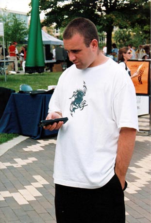 Anime In Northwest Ohio member Joe fiddling with a remote control outdoors. A modern observer might mistake him for holding a smartphone..