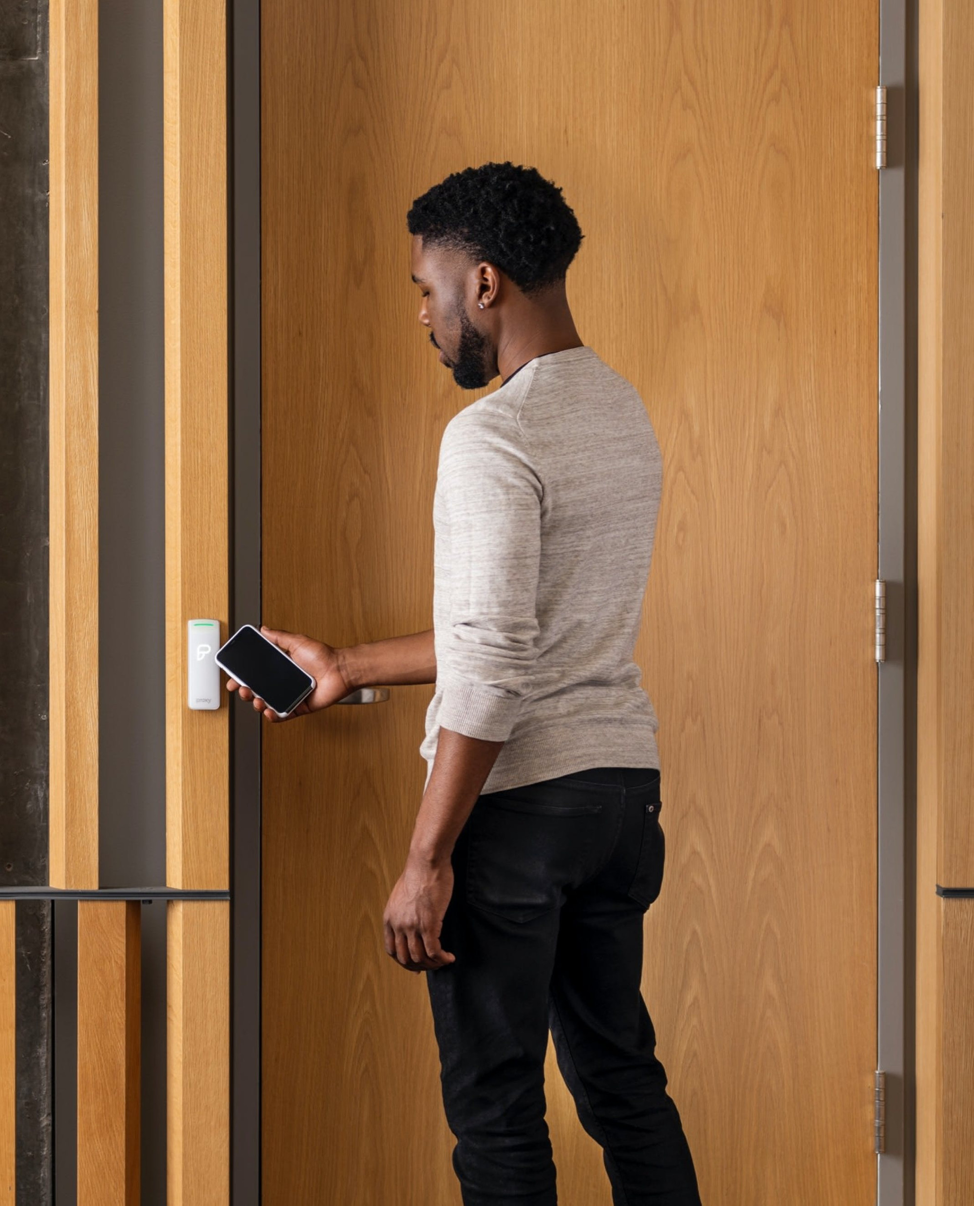 Man tapping his phone on a door reader to open it