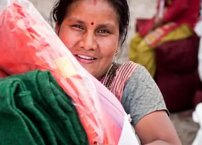 A woman collects blankets, a tarpaulin, and other necessities.