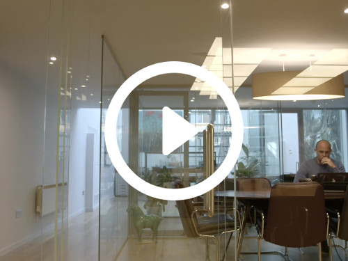 Modern office meeting space enclosed by interior glass walls containing brown metal framed chairs and black table Skype background