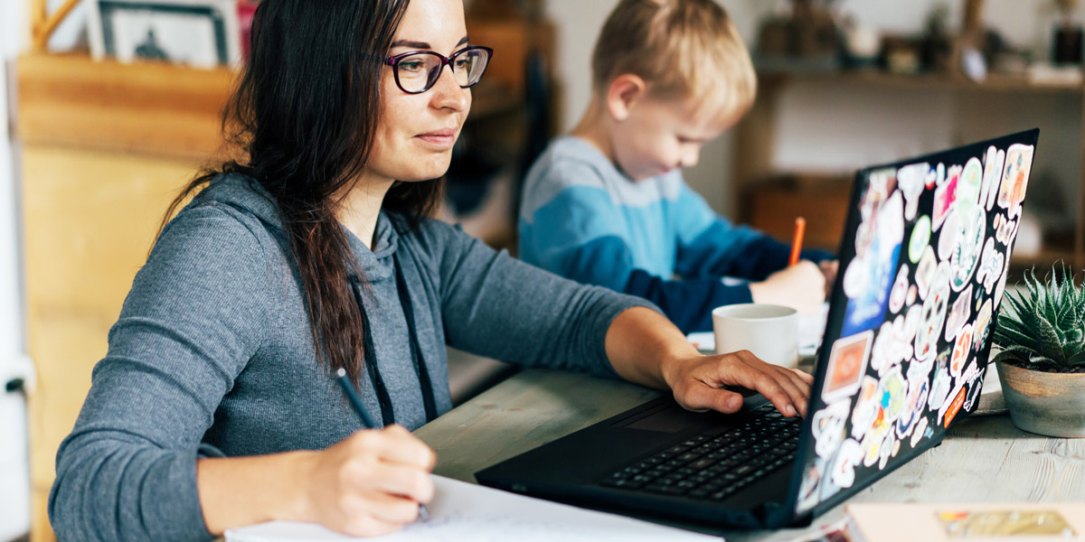What are the best web development certification programs? A woman working on a laptop with a child sitting next to her