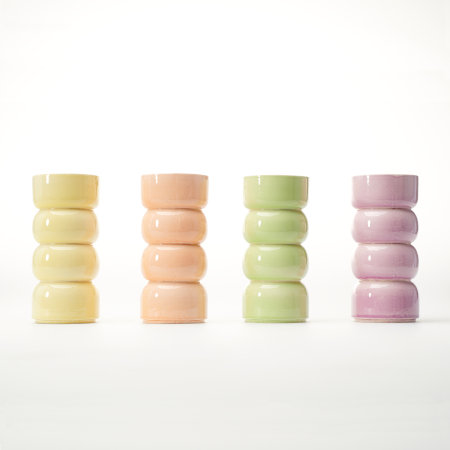 Four tall vessels, each having four donut-shaped sections, each a different colour; yellow, pale orange, pale green and pale magenta-purple.