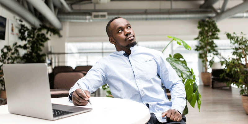 A user experience designer sitting at his desk with a laptop A UX designer sitting in front of his laptop, holding a pen