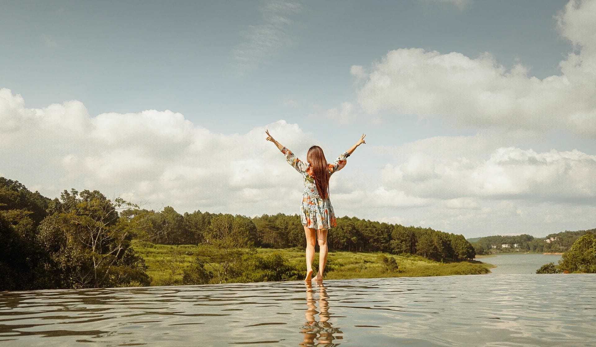 Women standing on the edge between water and a forest