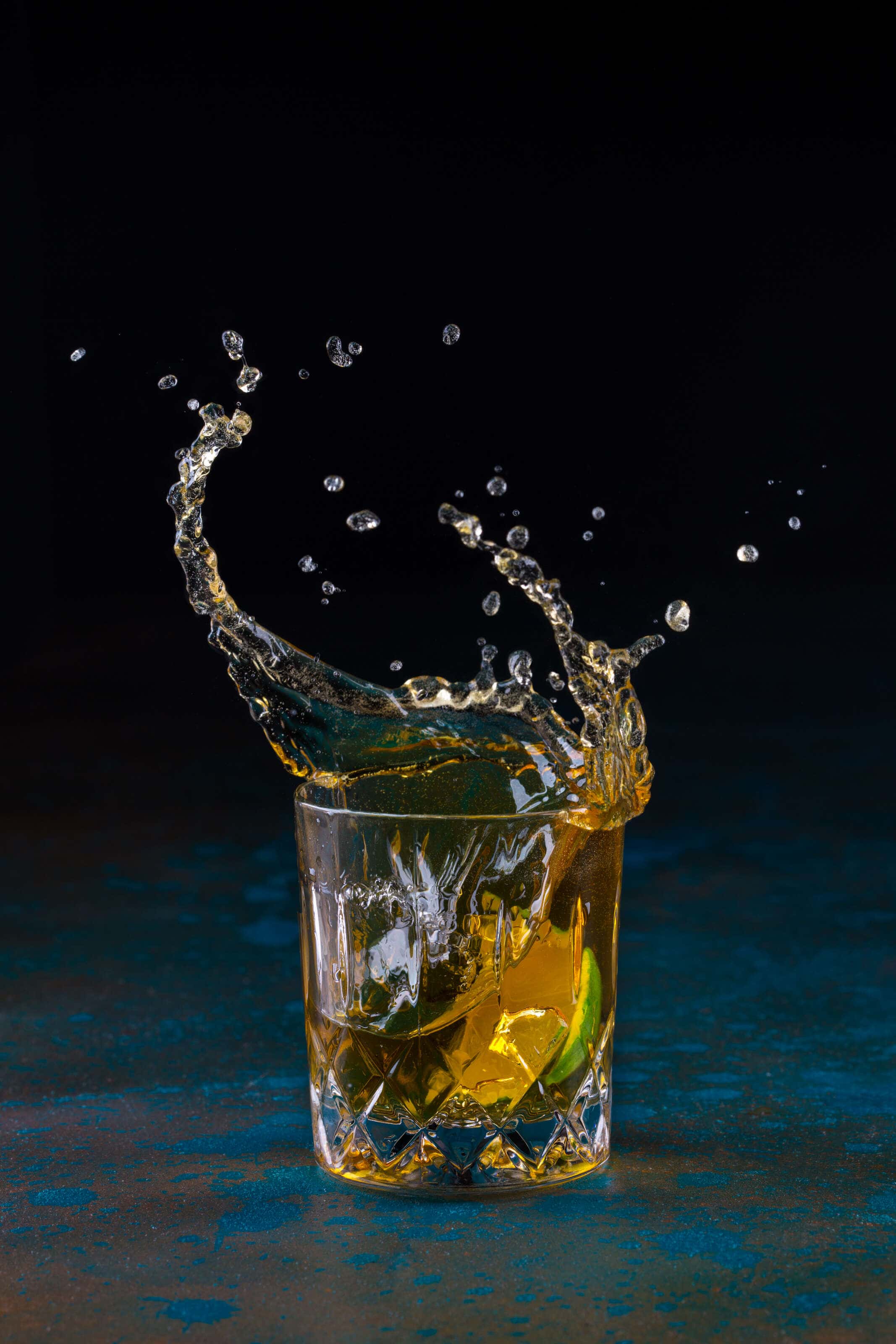 rum cocktail with a lime being dropped into it causing a splash.