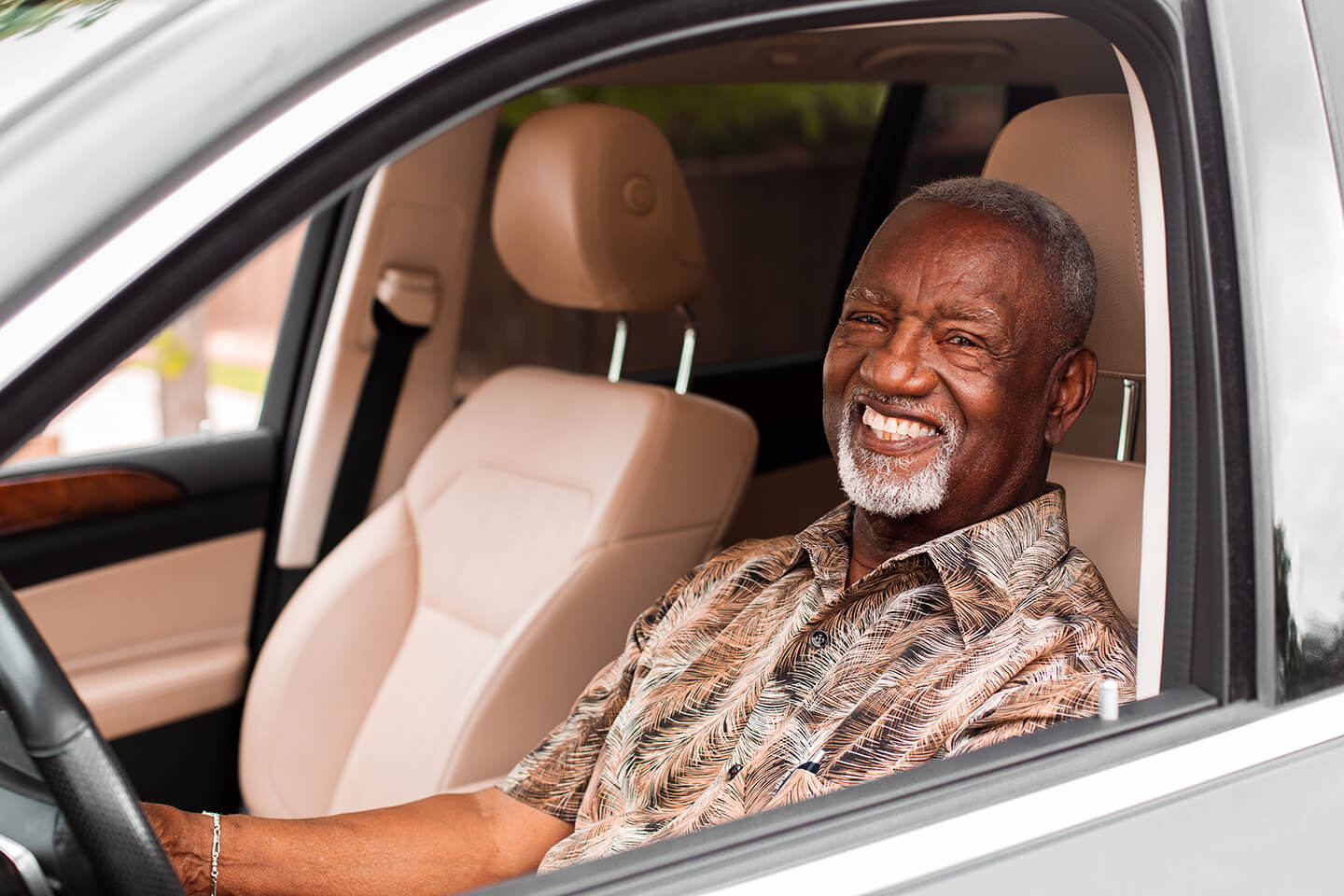 a smiling man driving his car