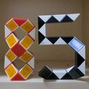 A pair of Rubik Snake like puzzles twisted into the shapes of an eight and a five.