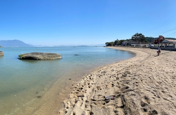 Vista panoramica da curta praia da Tapera, pegando a areia e o mar calmo atras, onde se vê algumas pedras grandes dentro da água