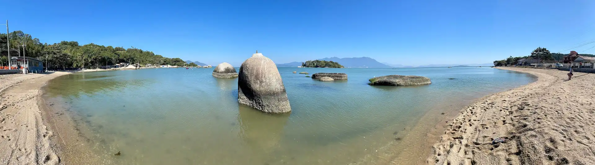 Vista panoramica da curta praia da Tapera, pegando a areia e o mar calmo atras, onde se vê algumas pedras grandes dentro da água