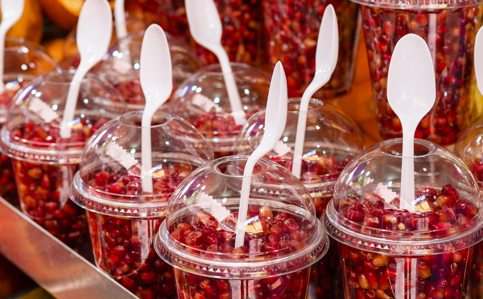 cups of red pomegranate seeds with spoons