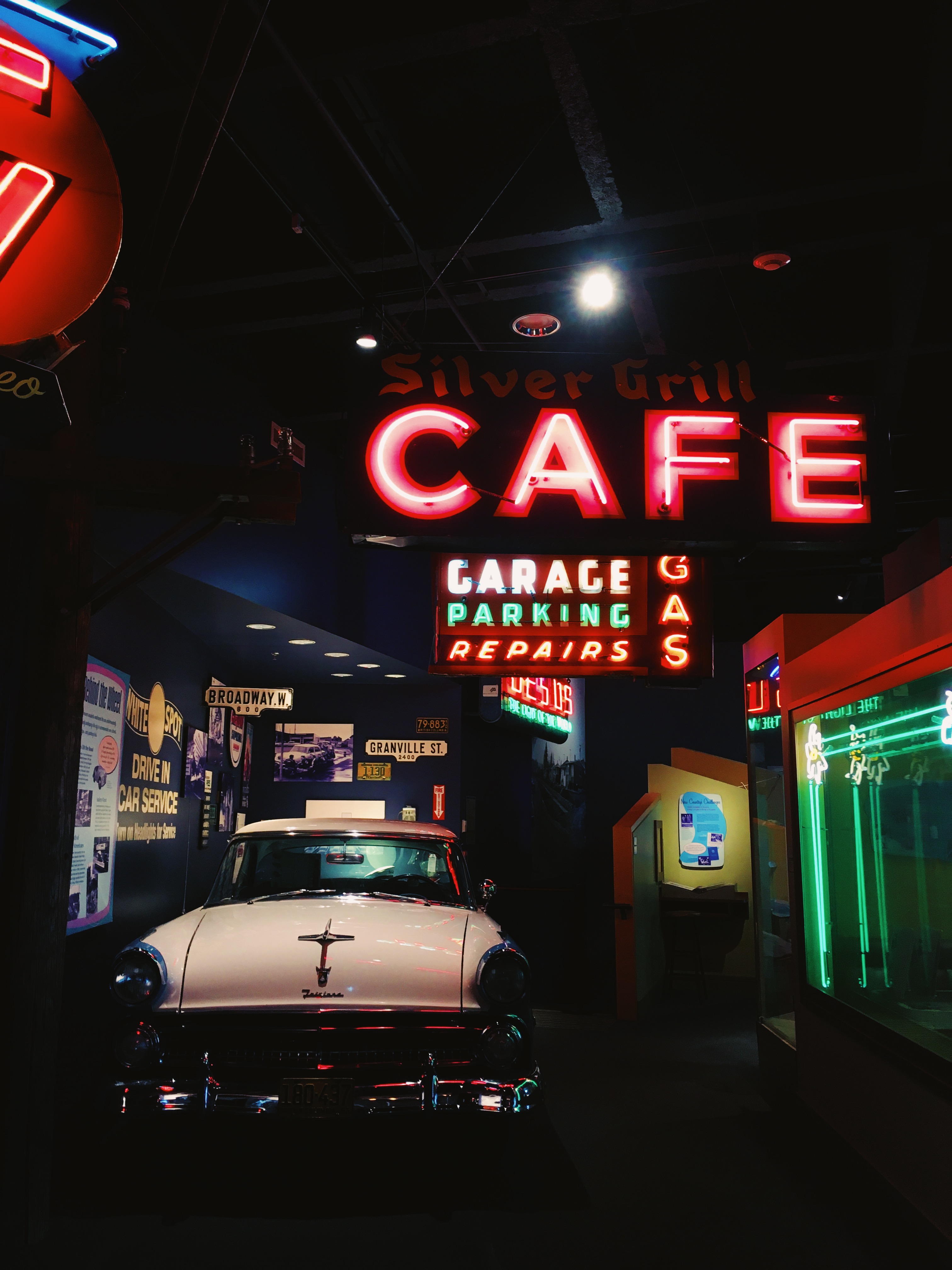 A 50s exhibit, with neon signs hanging above and a vintage car.