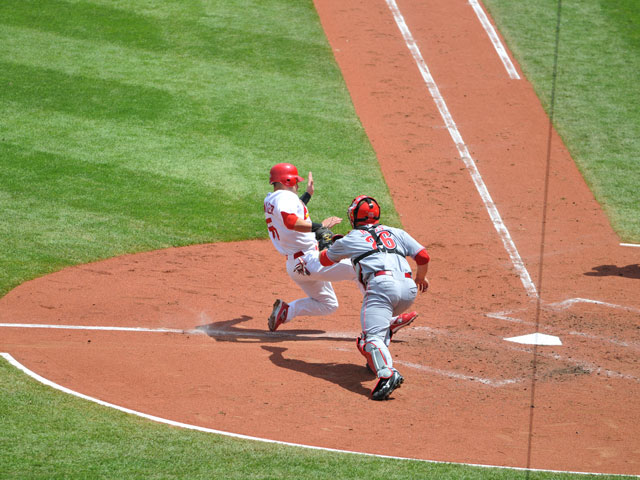 A runner trying to score while a catcher makes a play at home plate.