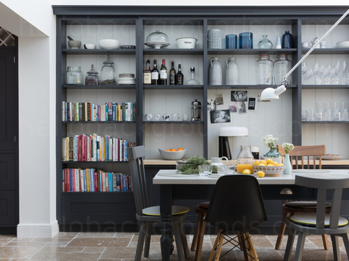 Airy dining area featuring large black storage shelves and a white table with black chairs of various designs Zoom background