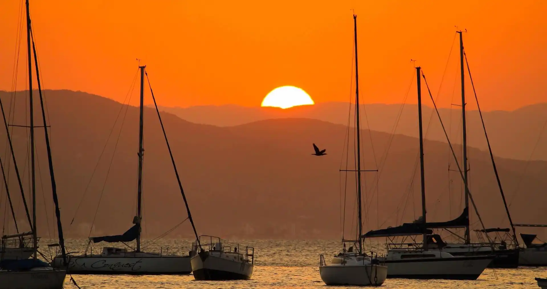 Pôr-do-sol com céu alaranjado e barcos na água