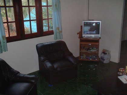 Wir betreten das ehrwürdige Gemäuer durch die hölzerne Vordertür und sehen uns dem Medienzimmer gegenüber. Die thailändische Standardcouch fehlt ebensowenig wie das in allen Häusern vorhandene Glascouchtischmodell (identisch mit dem im alten Haus --- man vergleiche bitte). Auf dem Tisch sehen wir ein Buch mit einem pinken Elefanten sowie verschiedene Drogenbestecks. Einige neckisch verteilte Sessel vervollständigen das noch recht karge Ambiente und geben zwischen durch einen Holzmarionettenelefanten namens Kah (Hubert Kah) bewachten Fernseher und Couch den Weg in die Partyhalle frei.
Die Partyhalle glänzt durch noch zu verplanende Mehrzweck-Leere, einen Kühlschrank und einer fest in den Boden eingemauerten Spüle unter der sich gar trefflich verschiedene Müllsorten verbergen lassen. Im Hintergrund sehen wir das Spa Beddig, in das wir aus Pietätsgründen nur kurz einen Blick werfen wollen.
Das Spa glänzt durch organisierte Gestaltung und charmante Fliesierung. Beachten Sie bitte die Feuchtigkeitscreme mit UV-Schutz sowie den allgegenwärtigen Jacko-Zerstäuber. Im Spiegel erkennt der geneigte Betrachter einen durch verschiedene Ereignisse in naher und ferner Vergangenheit verschlankten Autoren der die Wirkung des Blitzes geschickt zur Verwirrung des Blickes zu nutzen weiß.
Gehen wir weiter zur Spielwiese:
Sehen Sie das geräumige Bett, das geradezu auf Belegung wartet sowie die verschiedenen Fenster die nach draußen führen. Ein kleiner Schrank lädt zum Verweilen ein.
Und nun noch eine Außenansicht des Komplexes:
Beachten Sie bitte das erfahren platzierte Moped, es zieht sich wie ein roter Faden durch die schreiBBloga.de!
Vielen Dank für Ihren Besuch und kommen Sie bloß nicht wieder. Es sei denn, Sie bringen ein Geschenk mit. Danke.