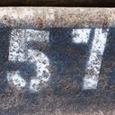 Fifty seven rustically stencilled on concrete, probably a curb number.