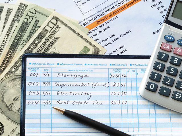 A person filling out a checkbook register and keeping good financial records