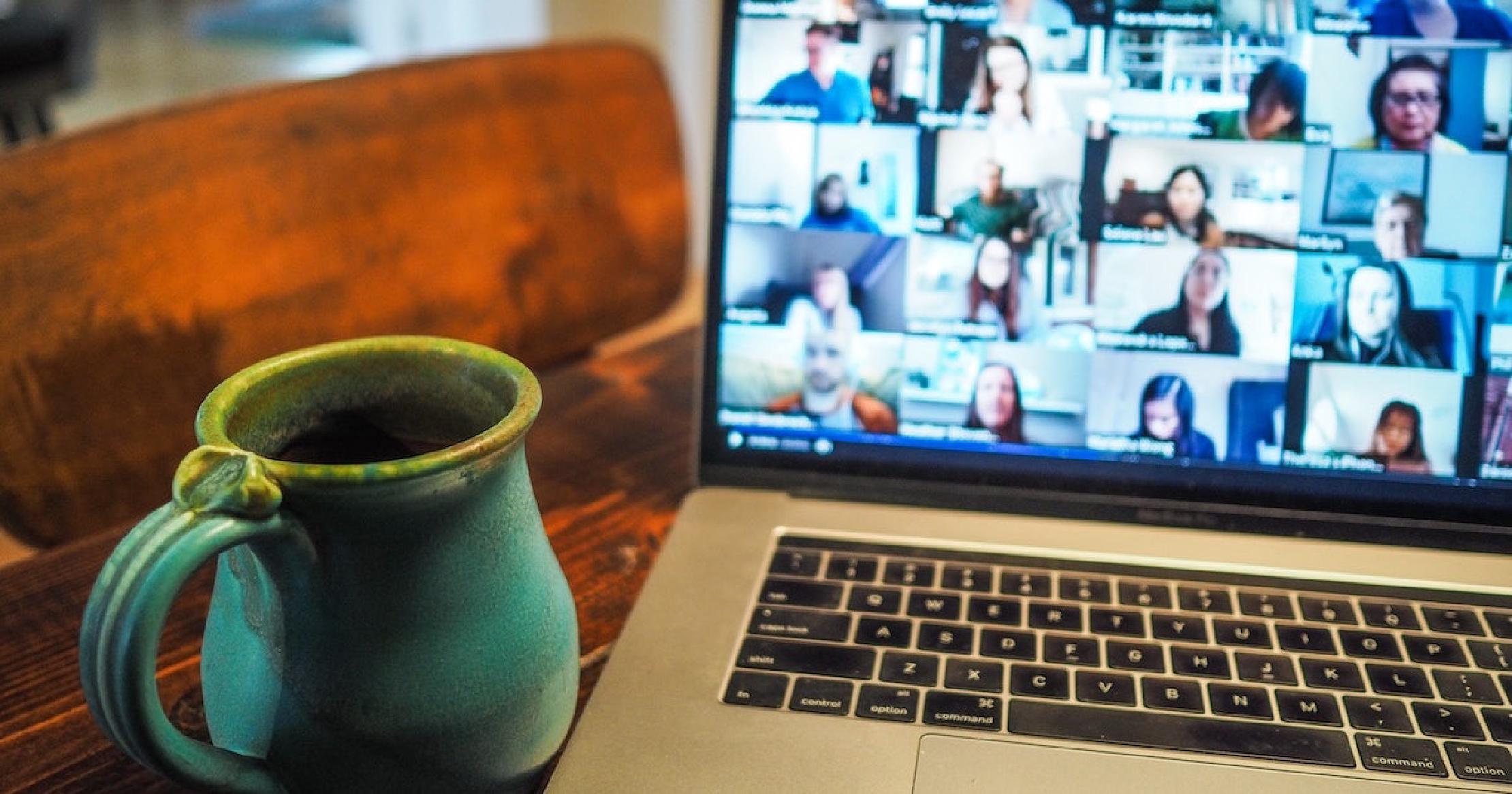 Thumbnail Coffee mug next to laptop with a blurred out Zoom screen with multiple people.