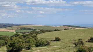 Green fields on the South Downs with a view of the East Sussex coastline towards Brighton.