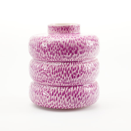 A magenta-purple vessel made up of three donut-shaped sections and a short neck, with an all over incised texture that holds the magenta glaze more intensely.