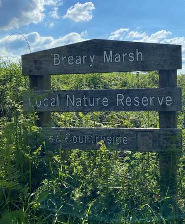 Breary Marsh entrance sign against a blue sky and grass