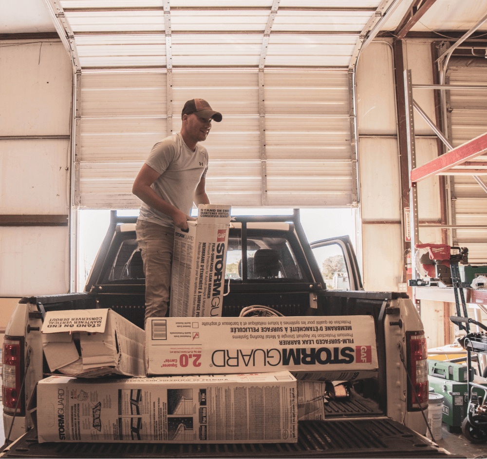 A worker standing in the back of a truck with construction supplies